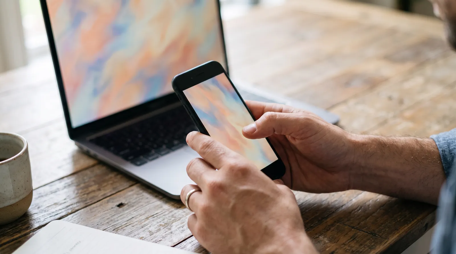 Hands tapping a smartphone beside an open laptop, showing a click being tracked